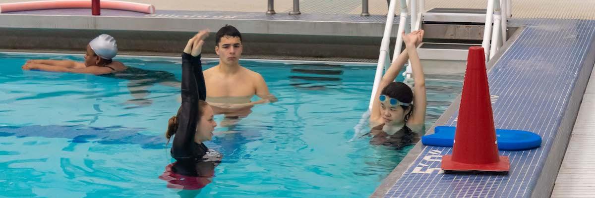Swim lesson instructor holding her arms above her head teaching a female student