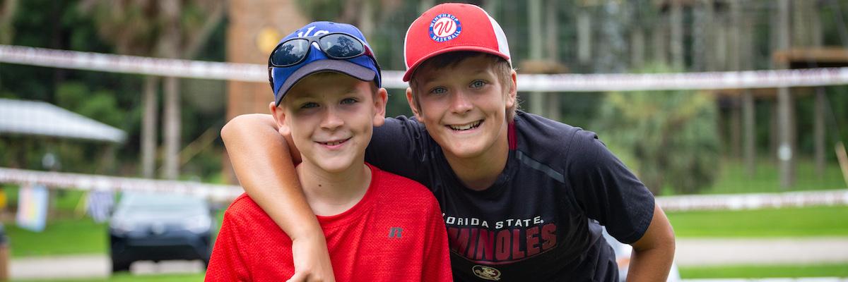 Two young male campers wearing hats. The one on the right has his arm around the one on the left.