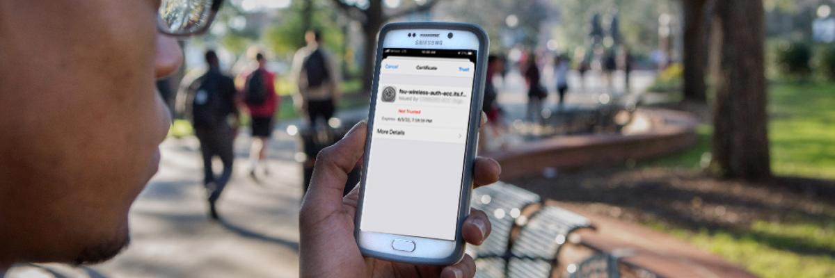 Student standing on FSU Legacy Walk looking at wireless certificate screen on cellphone