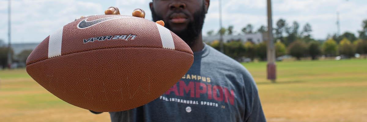 student holding a football in front of them