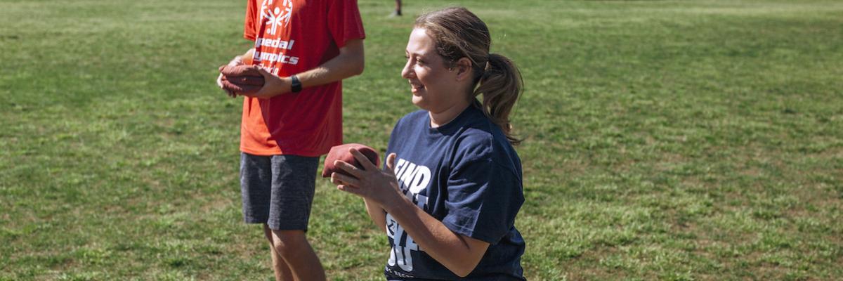 female student holding small beanbag to play cornhole with