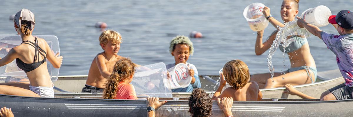 Kids in a canoe using buckets to pour water on each other