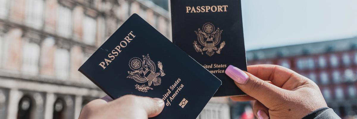 Passport books being held up in front of building. 