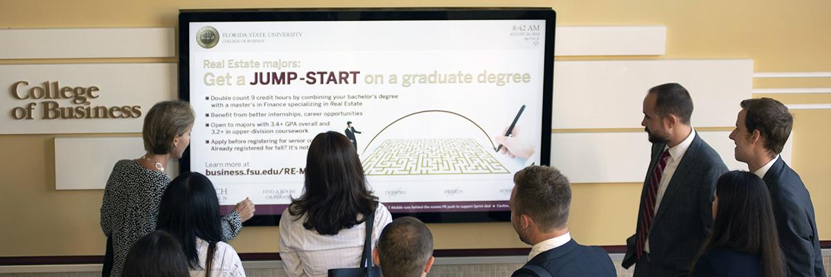 Group interacting with digital sign in FSU College of Business