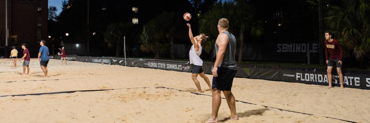 3 male students playing sand volleyball