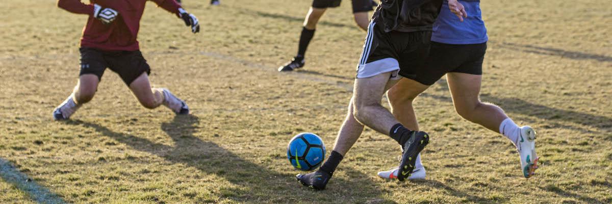 Three males playing soccer
