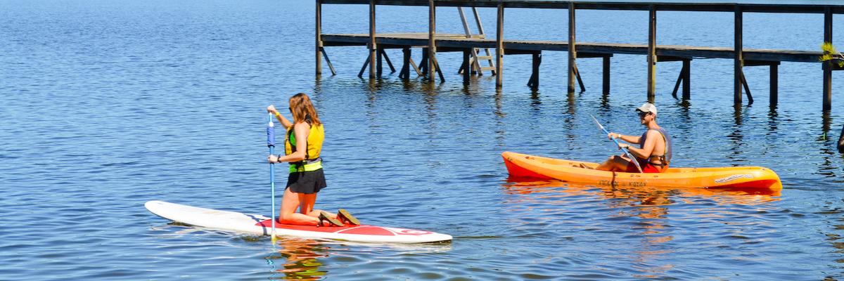 Two students kayaking in orange kayaks at the Rez Lakefront Park