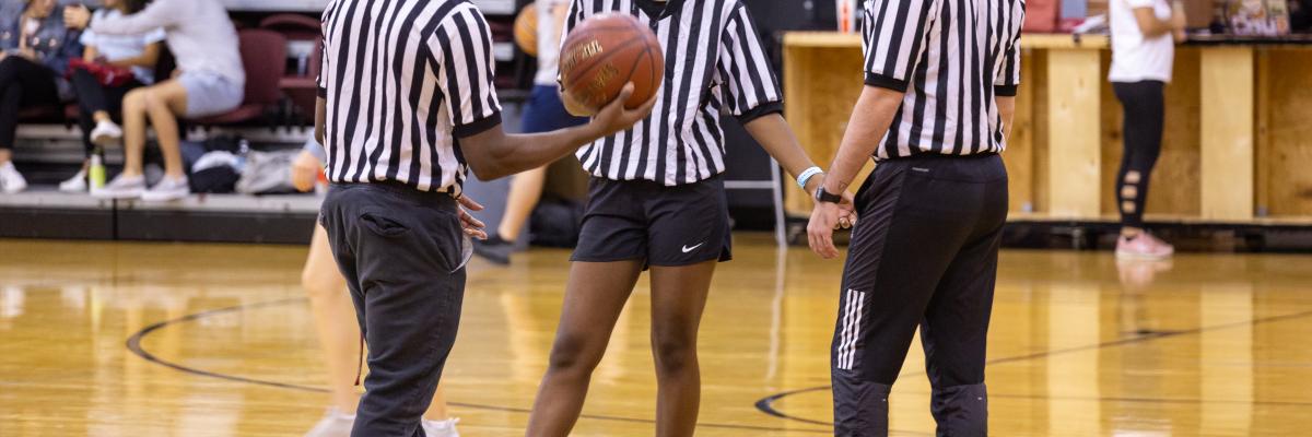 Picture of three student referees discussing on a basketball court