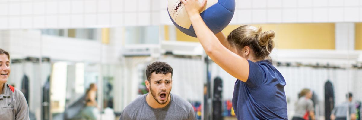 male student encouraging female student to throw slam ball