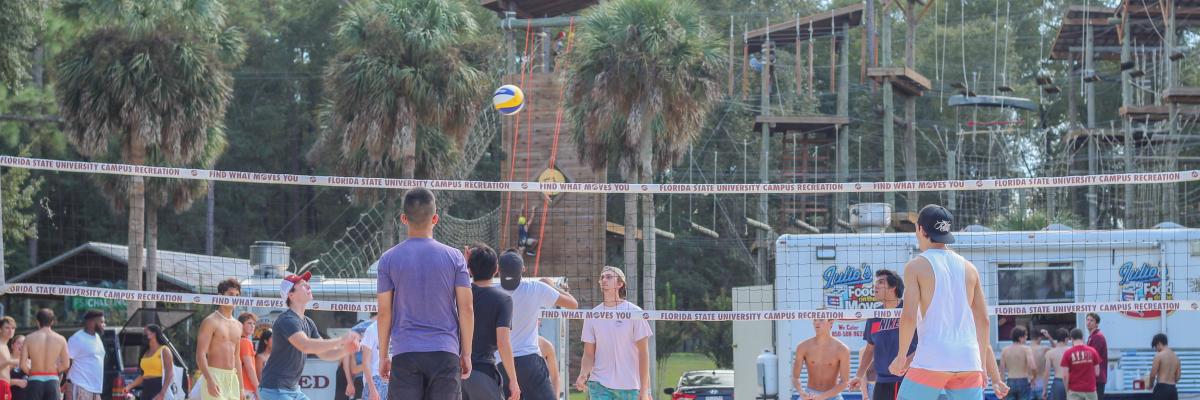 Group of people playing volleyball at Rez Lakefront Park with otherr groups of people in the background