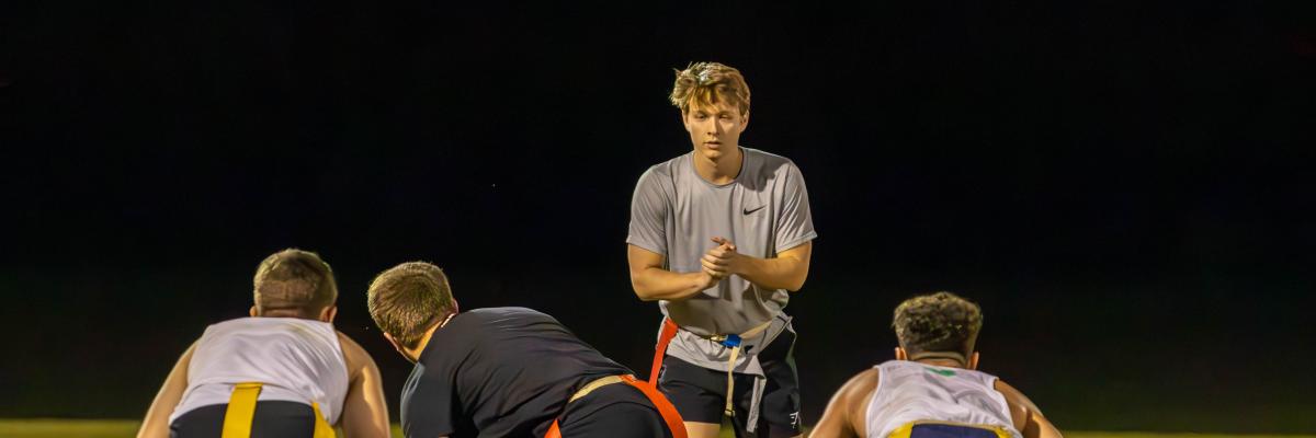 Four people playing flag football; focused on quarterback